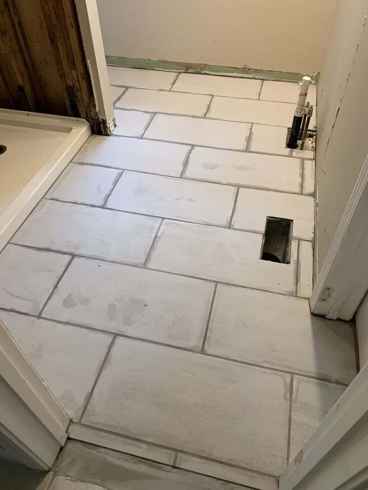 Bathroom floor in large white rectangular tile laid in an offset pattern beside a new shower base in Centretown, Ottawa