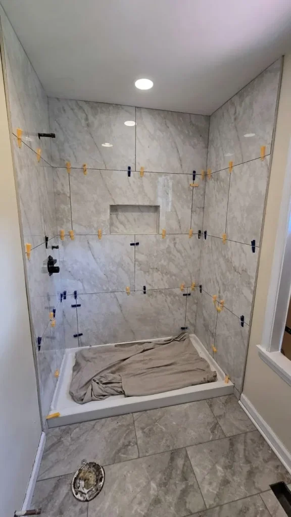 Shower walls tiled in large marble-look tile with a recessed niche, held flush with leveling clips, in a Centretown, Ottawa bathroom