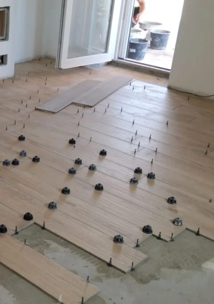 Wood-look plank tile laid in a staggered pattern with a leveling system near patio doors in Vanier, Ottawa